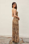 Woman wearing a leopard print strapless gown against a plain background