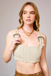 Woman wearing a beige corset top with suspenders against a plain background