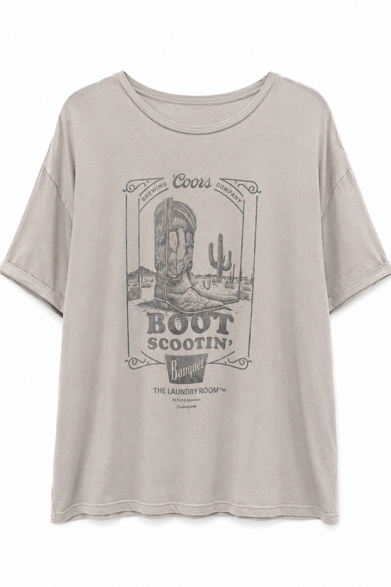 A light beige Coors Boot Scootin' graphic t-shirt with a vintage western-themed print featuring a cowboy boot, cactus, and desert scenery.