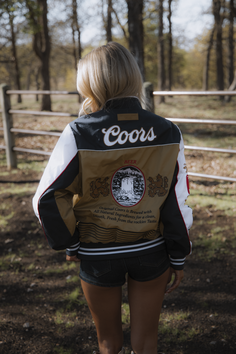 Person wearing a Coors-branded jacket in an outdoor setting