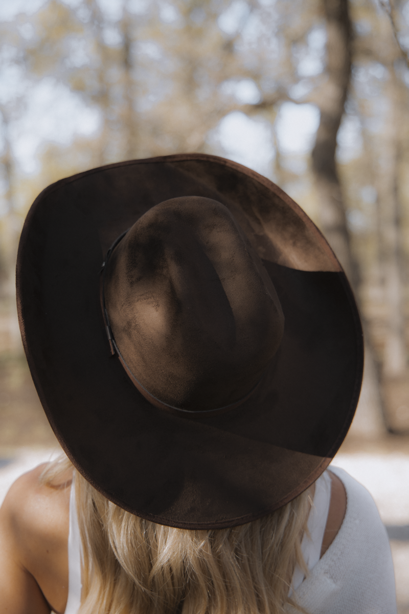 Person wearing a brown hat with a blurred natural background