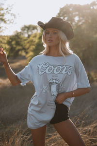 Woman wearing a Coors beer t-shirt and cowboy hat in a field