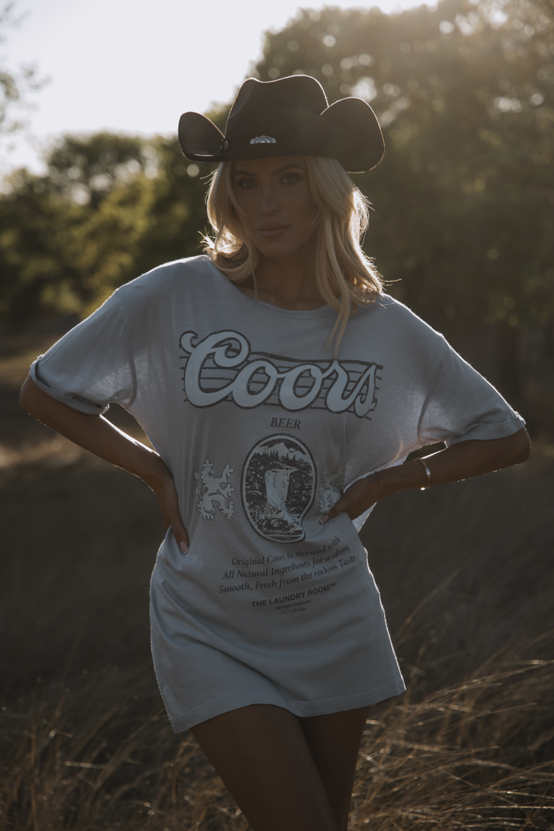 Woman wearing a Coors beer t-shirt and cowboy hat in a natural setting