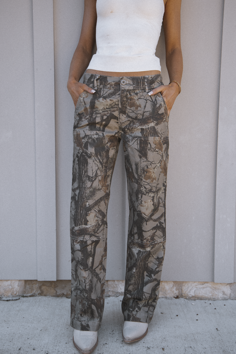 Person wearing camouflage pants with a plain background