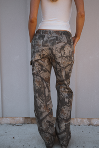 Person wearing camouflage pants against a plain background