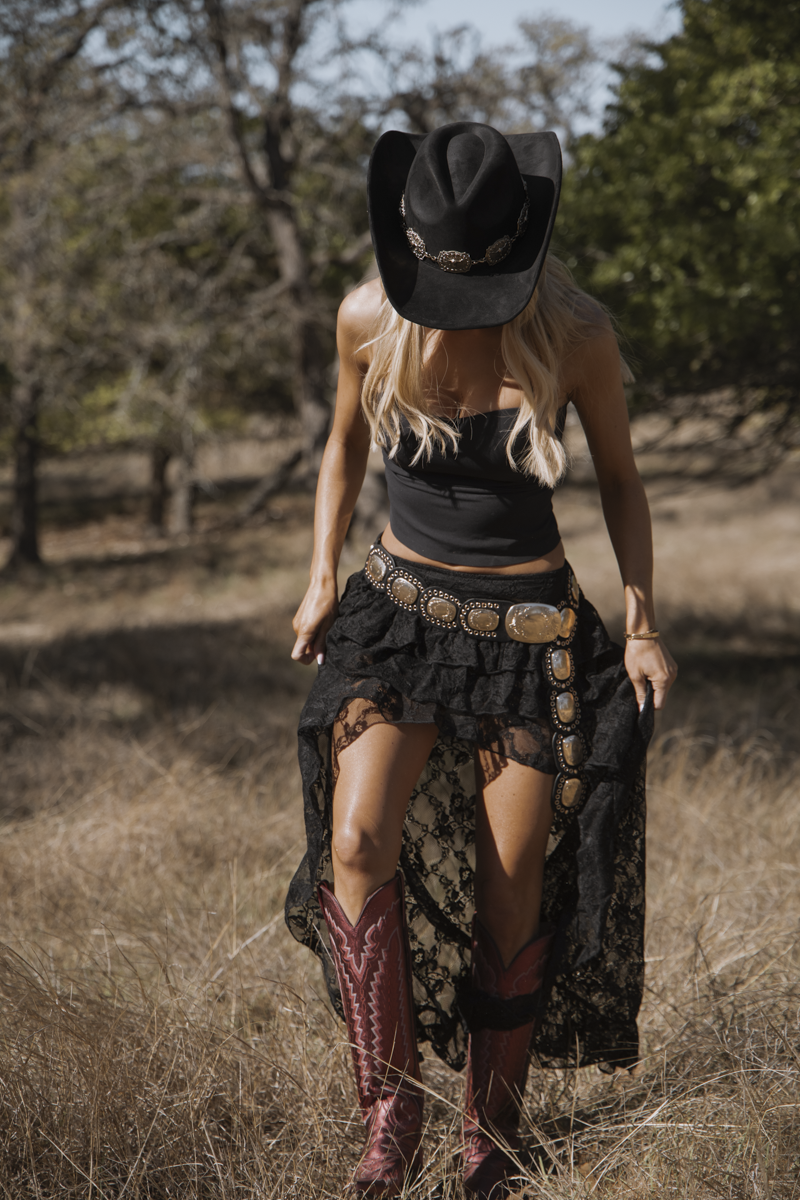 Person in cowboy hat and boots walking through a field