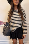 Person wearing a striped sweater and black skirt with a gray bag.