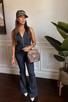Woman in denim outfit with cap and handbag indoors