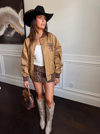 Woman in a stylish outfit with a cowboy hat, jacket, and boots indoors.