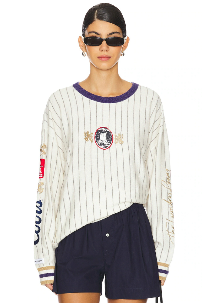 Person wearing a white and navy striped cashmere sweater with Coors designs and navy shorts on a white background