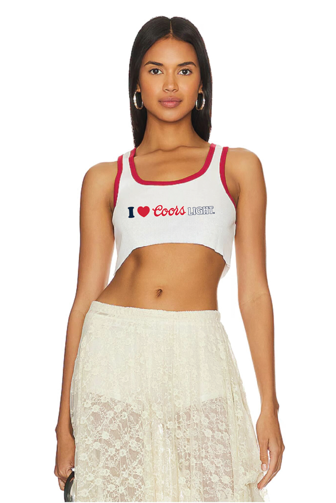 Woman wearing a white tank top with red straps and a graphic design, paired with a white lace skirt on a white background.