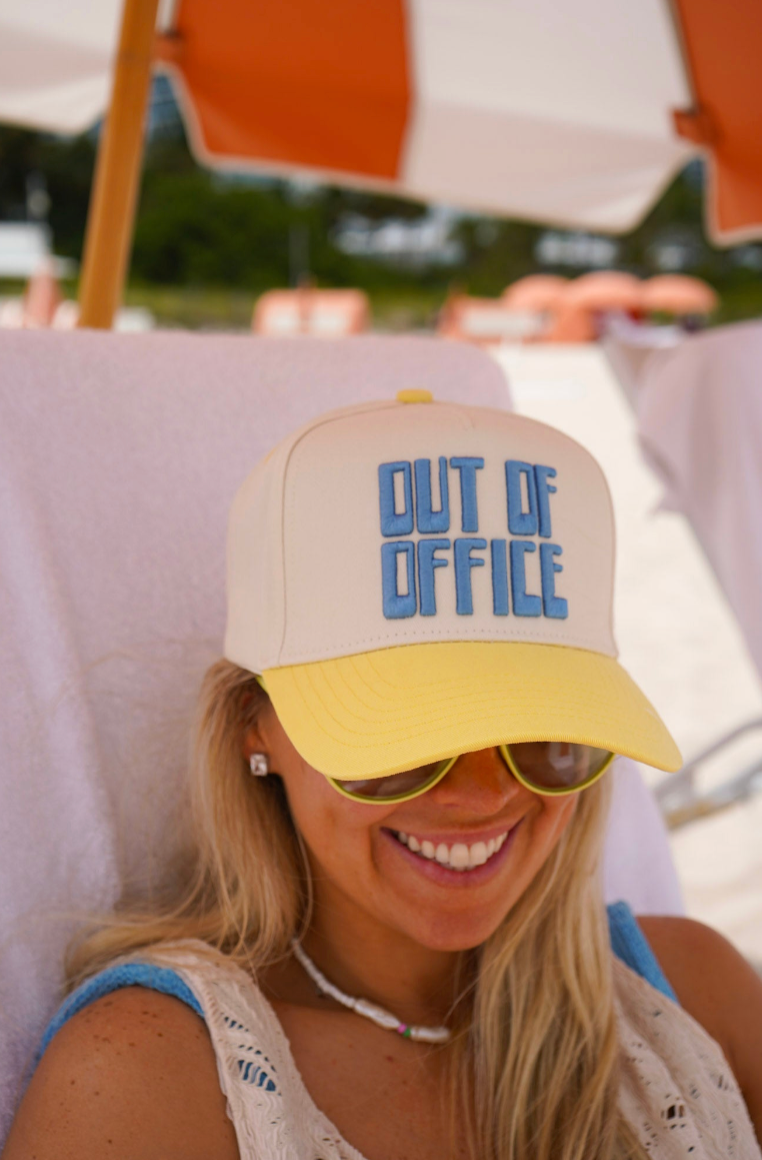 Woman wearing a 'Out of Office' cap at a beach.